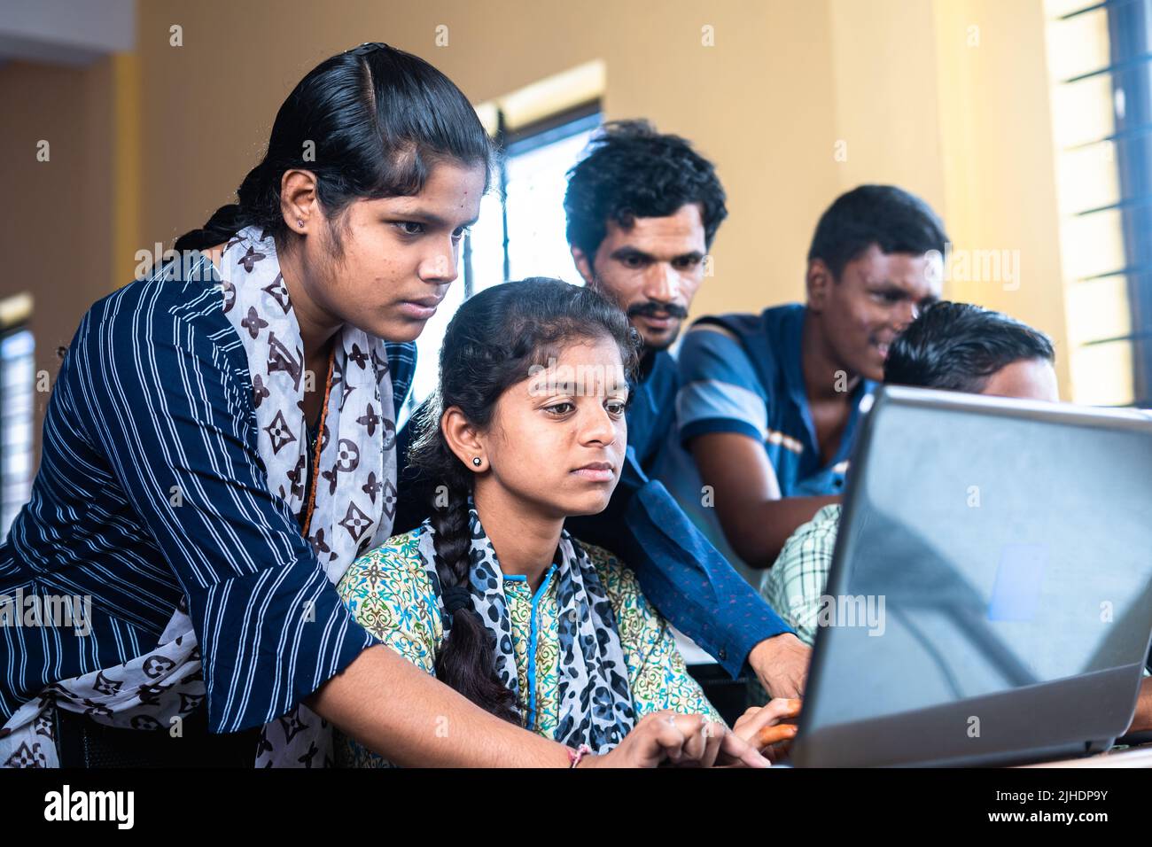 Grupos de estudiantes que usan seriamente la computadora portátil en el aula - concepto de tecnología, educación y autoaprendizaje Foto de stock