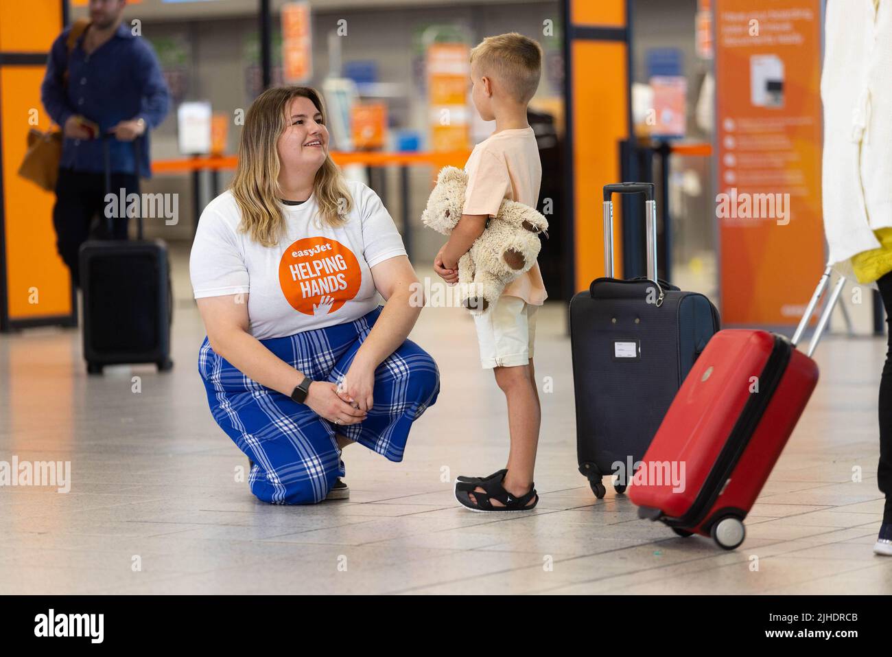 Cleo Greaves, asistente de atención al cliente de easyJet, ayuda a una familia joven en el aeropuerto de Luton mientras la aerolínea lanza su nueva línea de atención al cliente familiar. Fecha de emisión: Lunes 18 de julio de 2022. Foto de stock