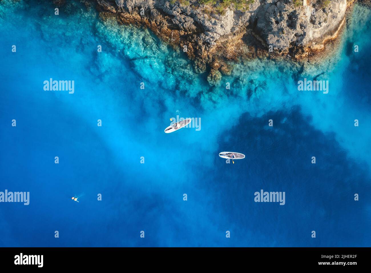 Vista aérea de la gente en tablas de sup. flotantes en el mar azul Foto de stock