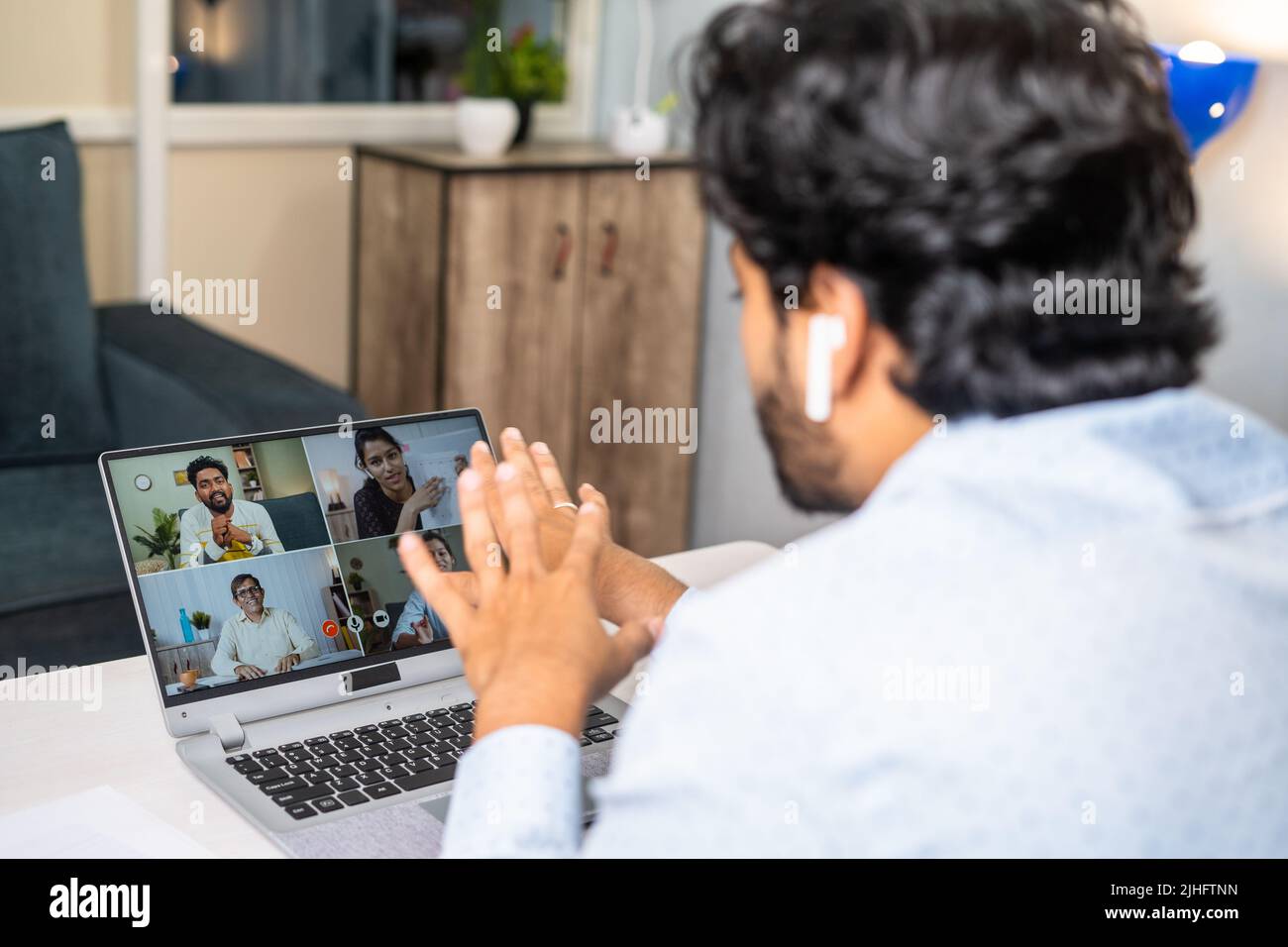 Un joven hombre de negocios que realiza una videollamada con sus compañeros en el ordenador portátil de la oficina: Concepto de formación en línea, reunión corporativa y proyecto Foto de stock