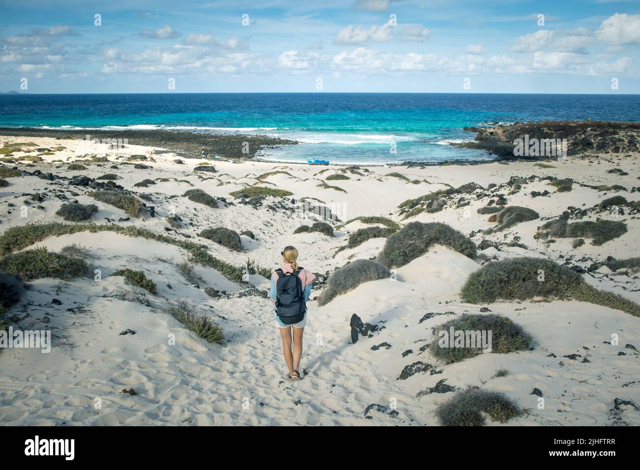 Turista mujer visitando la playa blanca de Caleta del Mojón Blanco. Playa de arena desértica y costa escarpada. Orzola, Lanzarote, Islas Canarias, España Foto de stock
