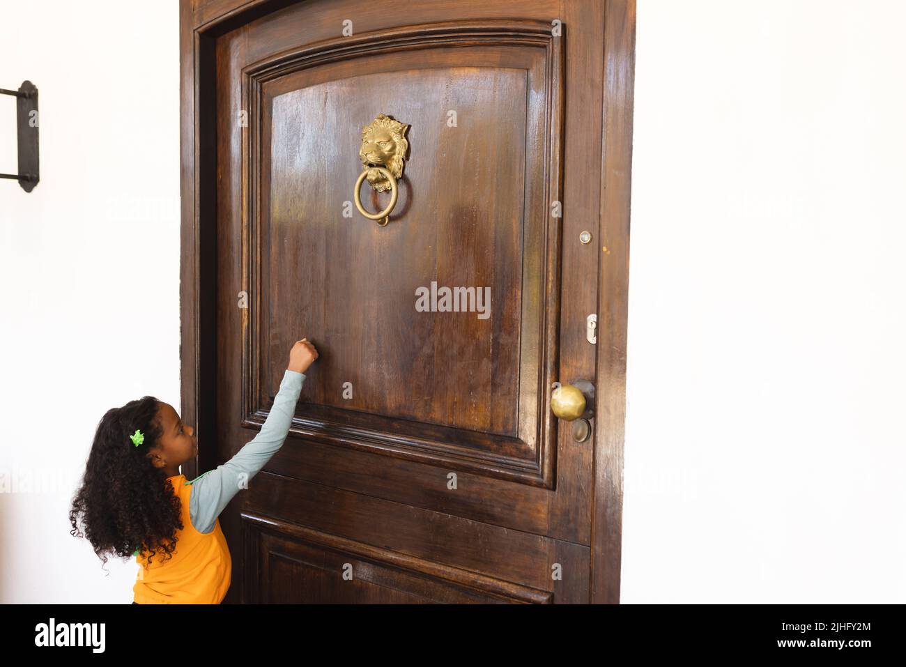 Imagen de una niña afroamericana con disfraz de halloween tocando a las puertas Foto de stock