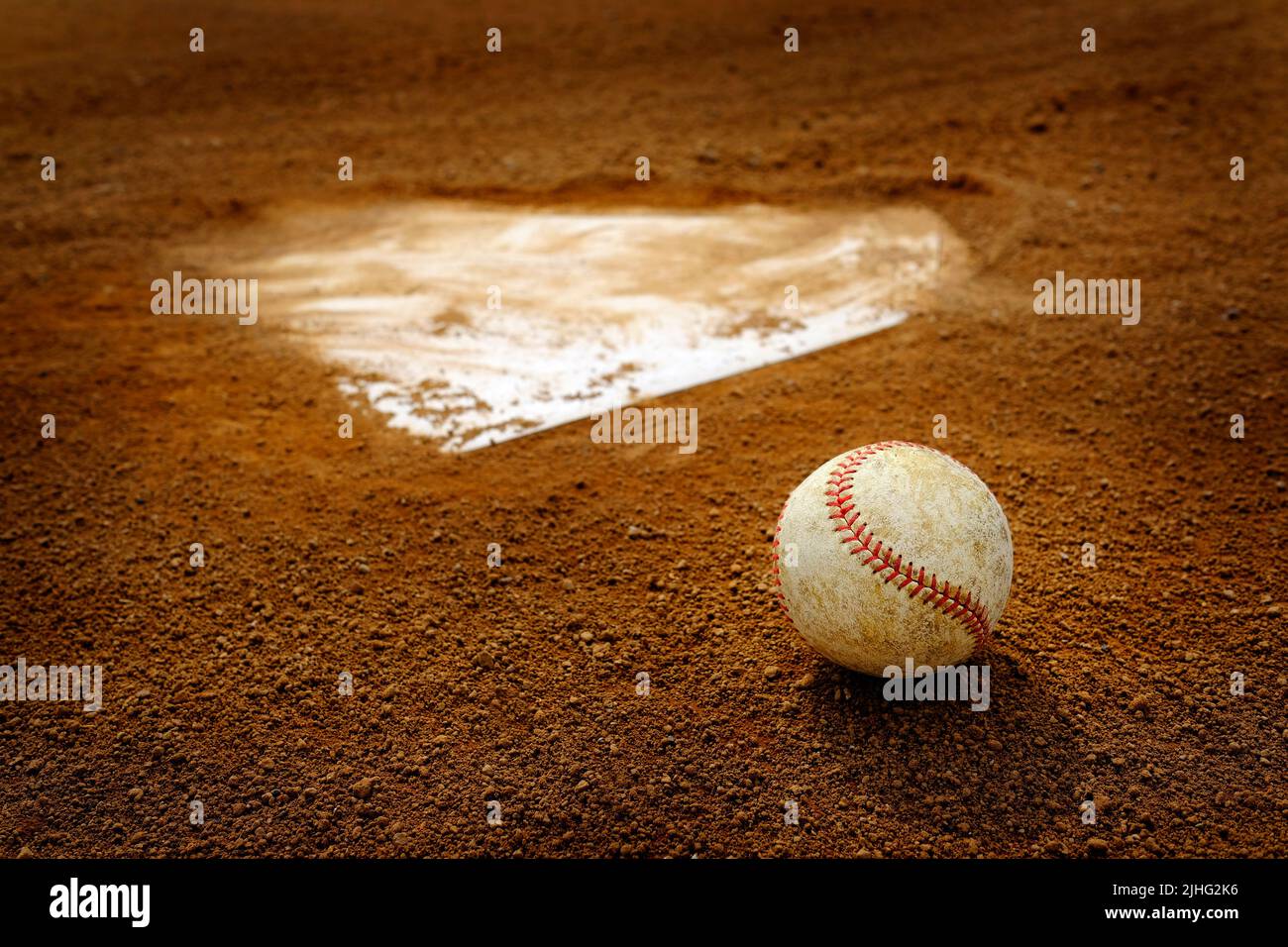 Béisbol de cuero viejo en el campo de la tierra por el plato de la casa o una base Foto de stock