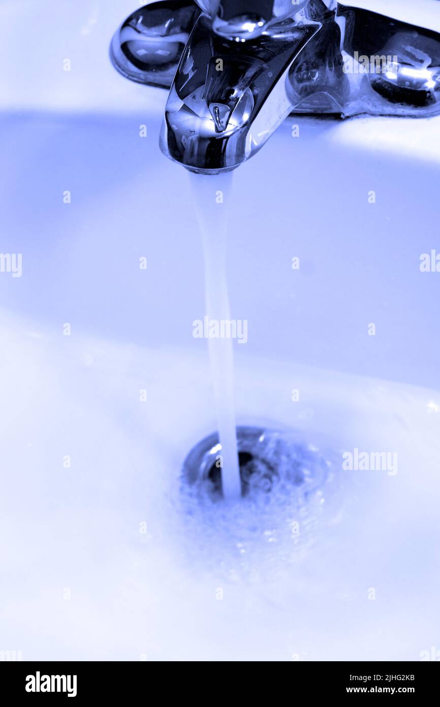 Pica con agua del grifo fluyendo o corriendo en el lavabo bajando por el desagüe Foto de stock