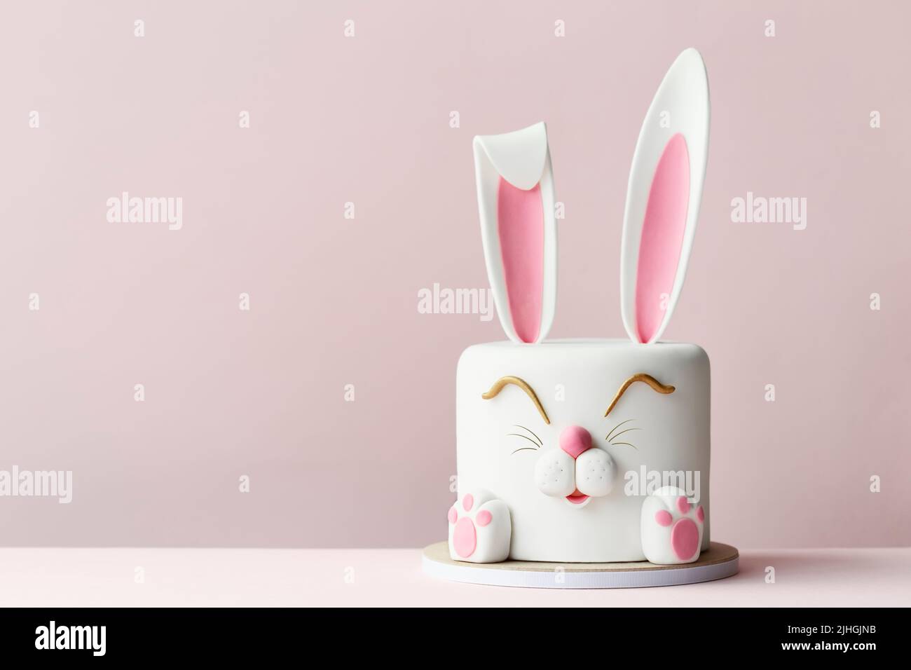 Pastel de celebración de conejito de Pascua sobre un fondo rosa Foto de stock
