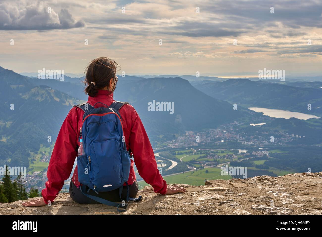 Retrato de una mujer viajera en las montañas. concepto de aventura, viajes  y senderismo. una mujer feliz con una gorra roja disfrutando de la luz del  sol durante una caminata en las