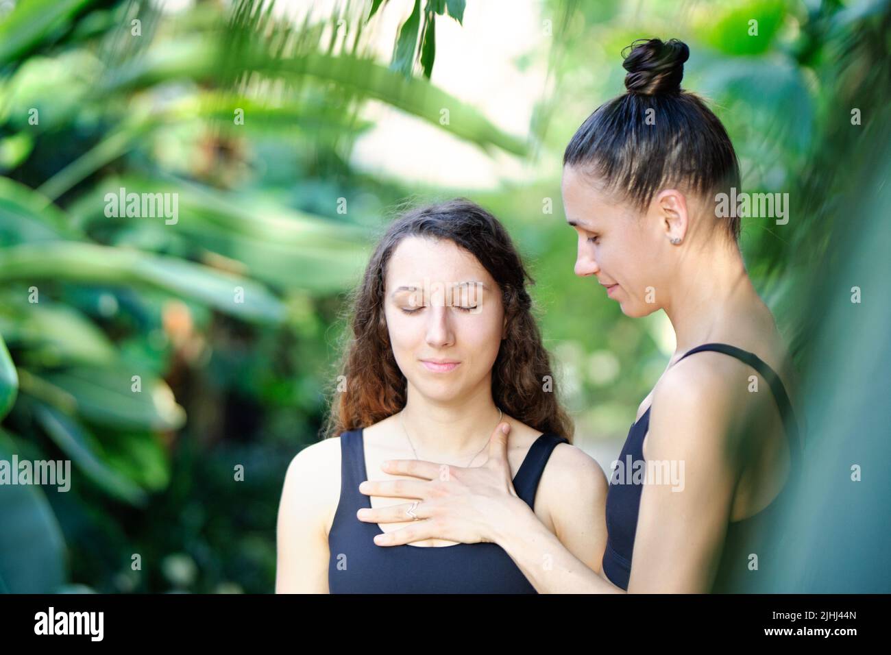 Concepto de yoga, meditación y terapia de sonido. Hermosa niña en sesión de yoga con su profesor de yoga y meditación en el trear de yoga tropical Foto de stock