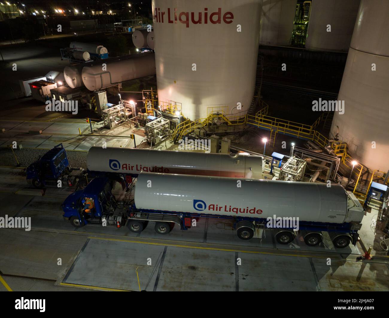 Vista aérea de los camiones de Air Liquide que se llenan en una instalación de Air Liquide, un proveedor de servicios y gases industriales, vista de noche. Foto de stock