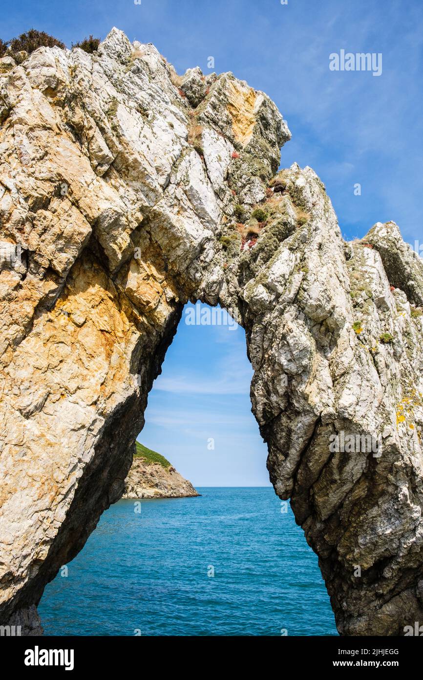 Vista a través de un arco natural de roca blanca en la bahía de Porth Wen. Cemaes, Isla de Anglesey, Gales, Reino Unido, Gran Bretaña Foto de stock