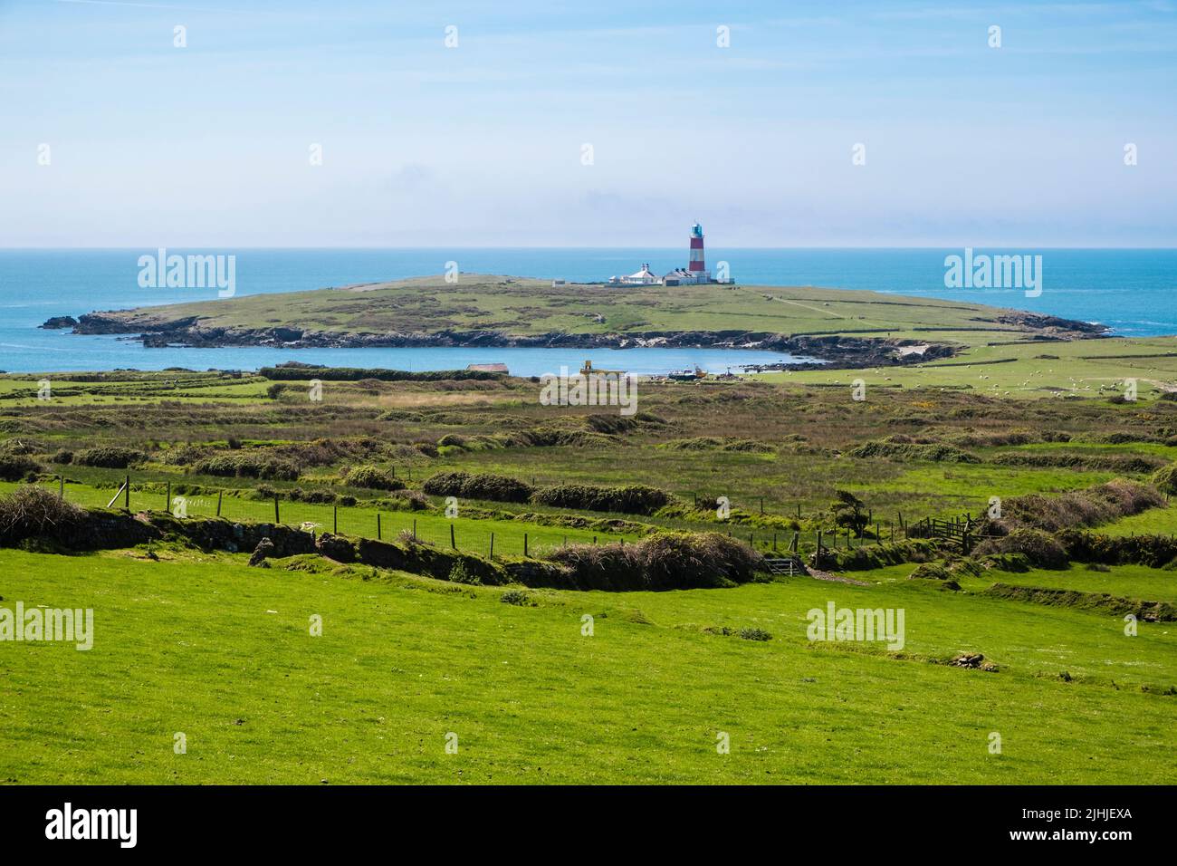 Vista a través de la campiña verde hasta el faro en Ynys Enlli o Bardsey Island, península de Llyn, Gwynedd, norte de Gales, Reino Unido, Gran Bretaña Foto de stock