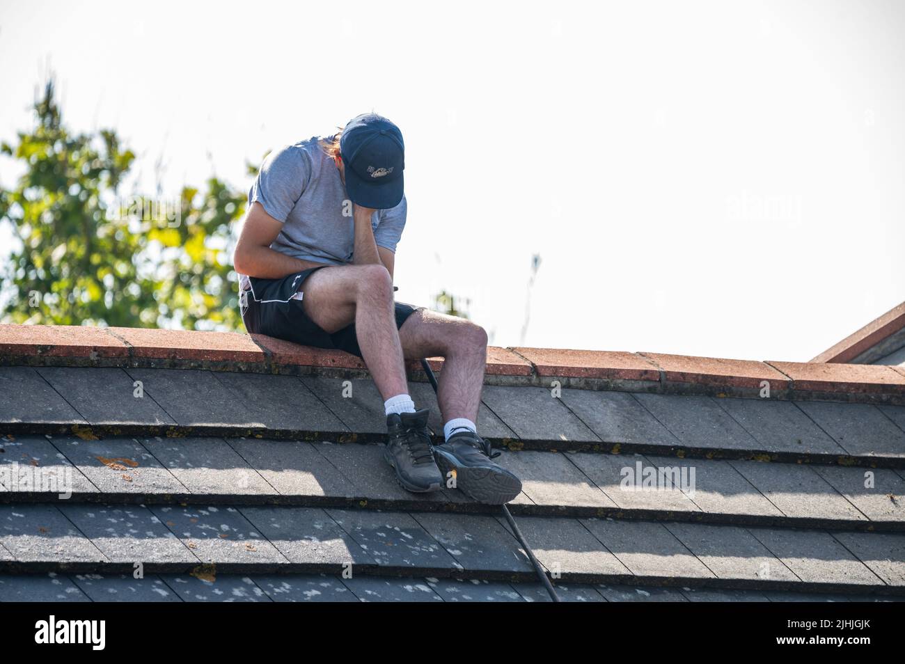 Rustington, West Sussex, Reino Unido. Martes 19th de julio de 2022. Un hombre se sienta esta mañana en el tejado de una casa en el calor abrasador mientras el calor continúa incesar, cerca de la costa sur. Crédito: Geoff Smith/Alamy Live News Foto de stock