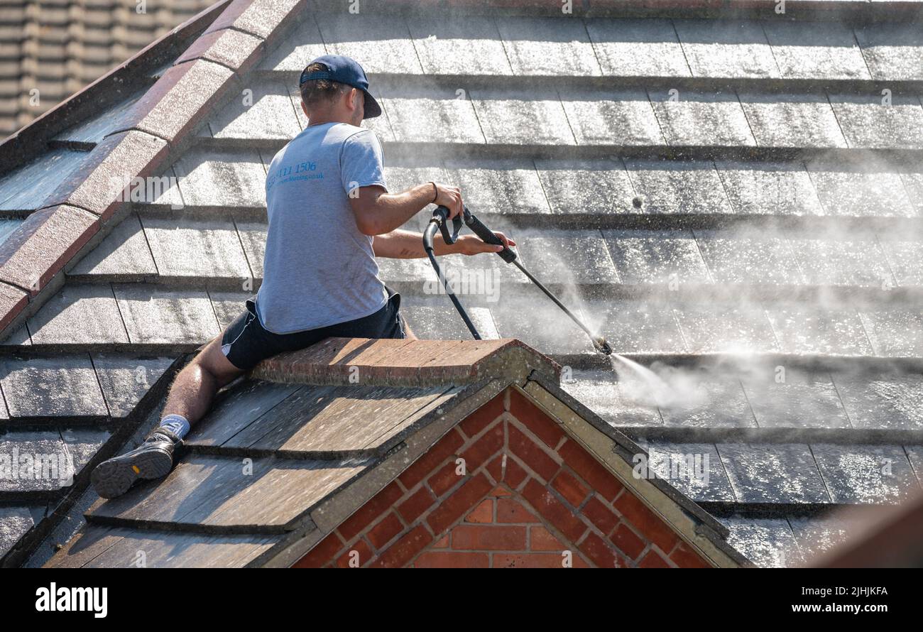 Rustington, West Sussex, Reino Unido. Martes 19th de julio de 2022. Un hombre utiliza un chorro de agua para limpiar el techo de una casa esta mañana mientras el calor continúa incesar, cerca de la costa sur. Crédito: Geoff Smith/Alamy Live News Foto de stock