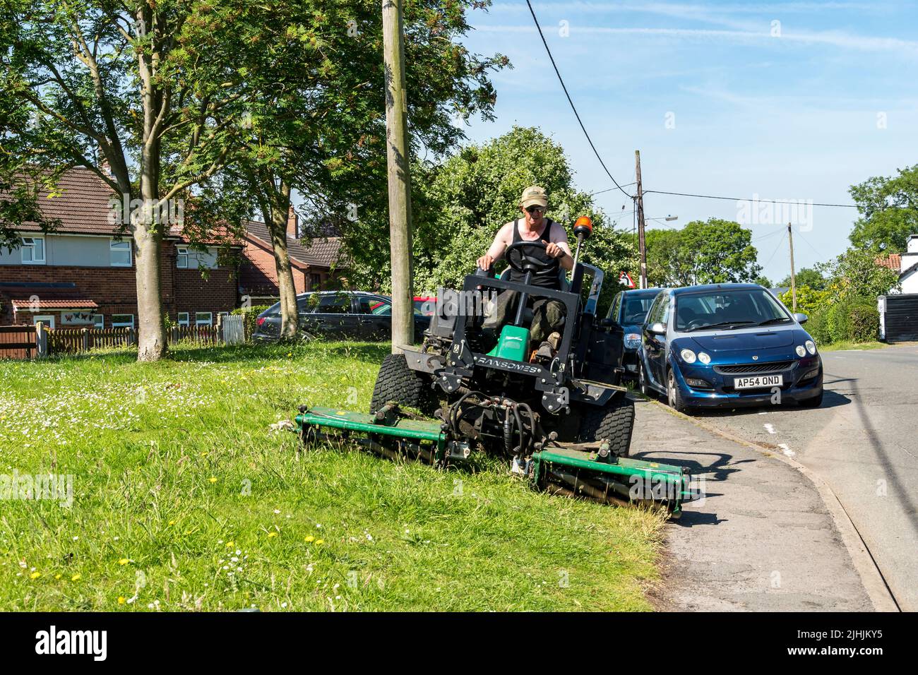 Contratista cortando verges de hierba con paseo en la máquina de segar High street Cherry Willingham Lincolnshire 2022 Foto de stock