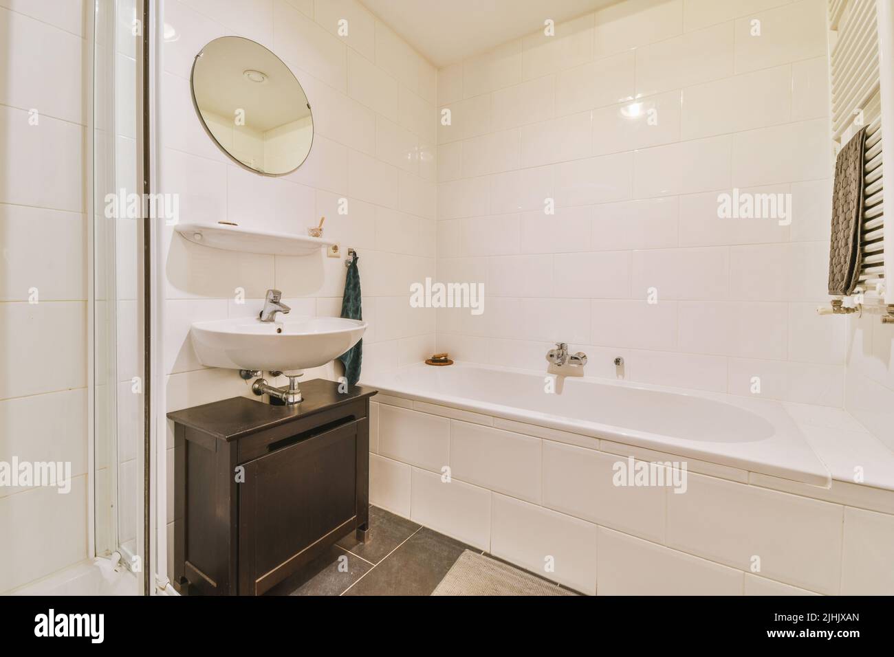 Bañera y cabina de ducha con azulejos y pared de cristal situada