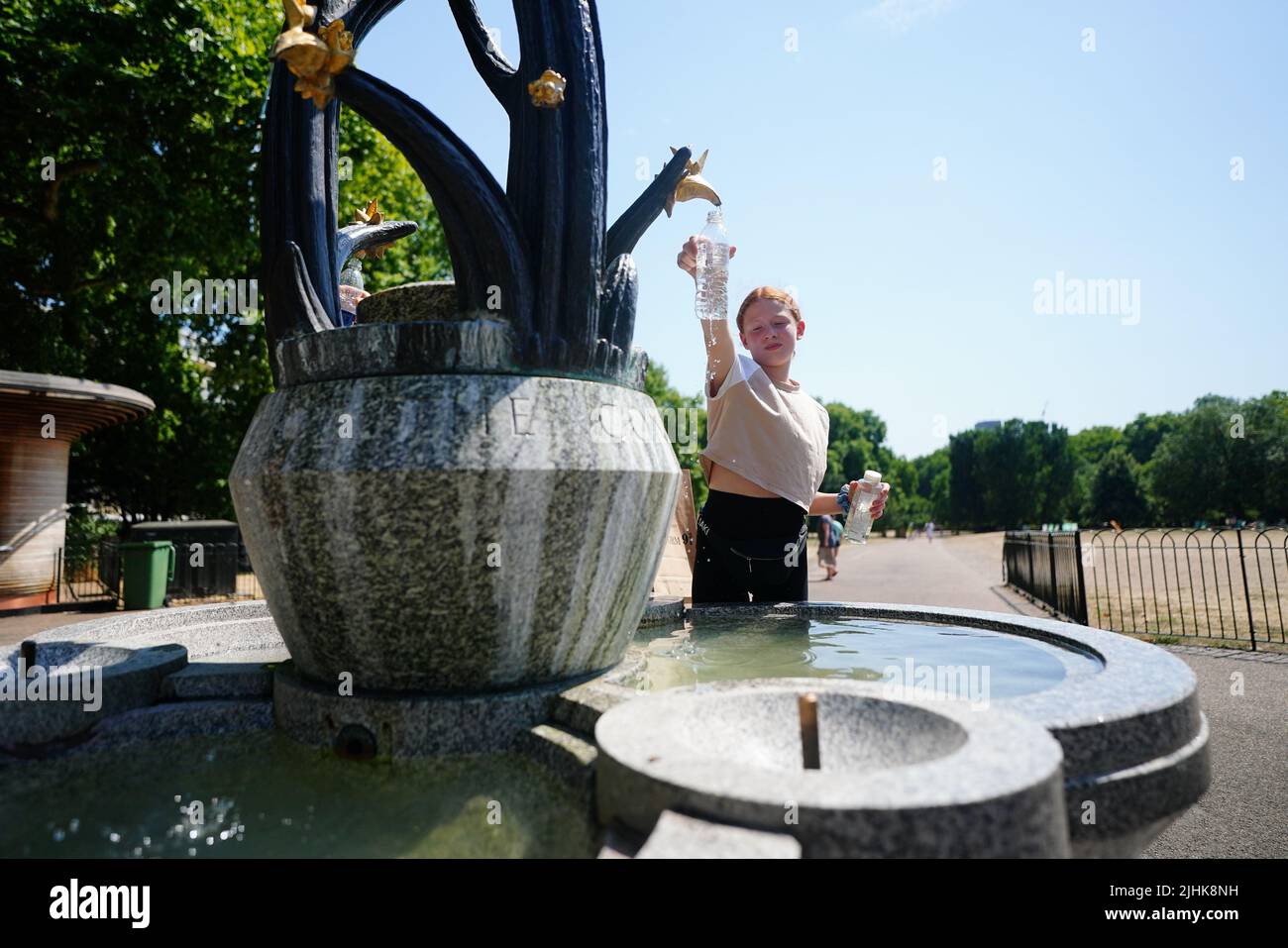 Una niña llena una botella de agua de una fuente de agua en Green Park, en el centro de Londres. Las temperaturas han alcanzado los 40C por primera vez registrados en el Reino Unido, con 40,2C registradas provisionalmente en Londres Heathrow, ha indicado la Oficina del MET. Fecha de la foto: Martes 19 de julio de 2022. Foto de stock