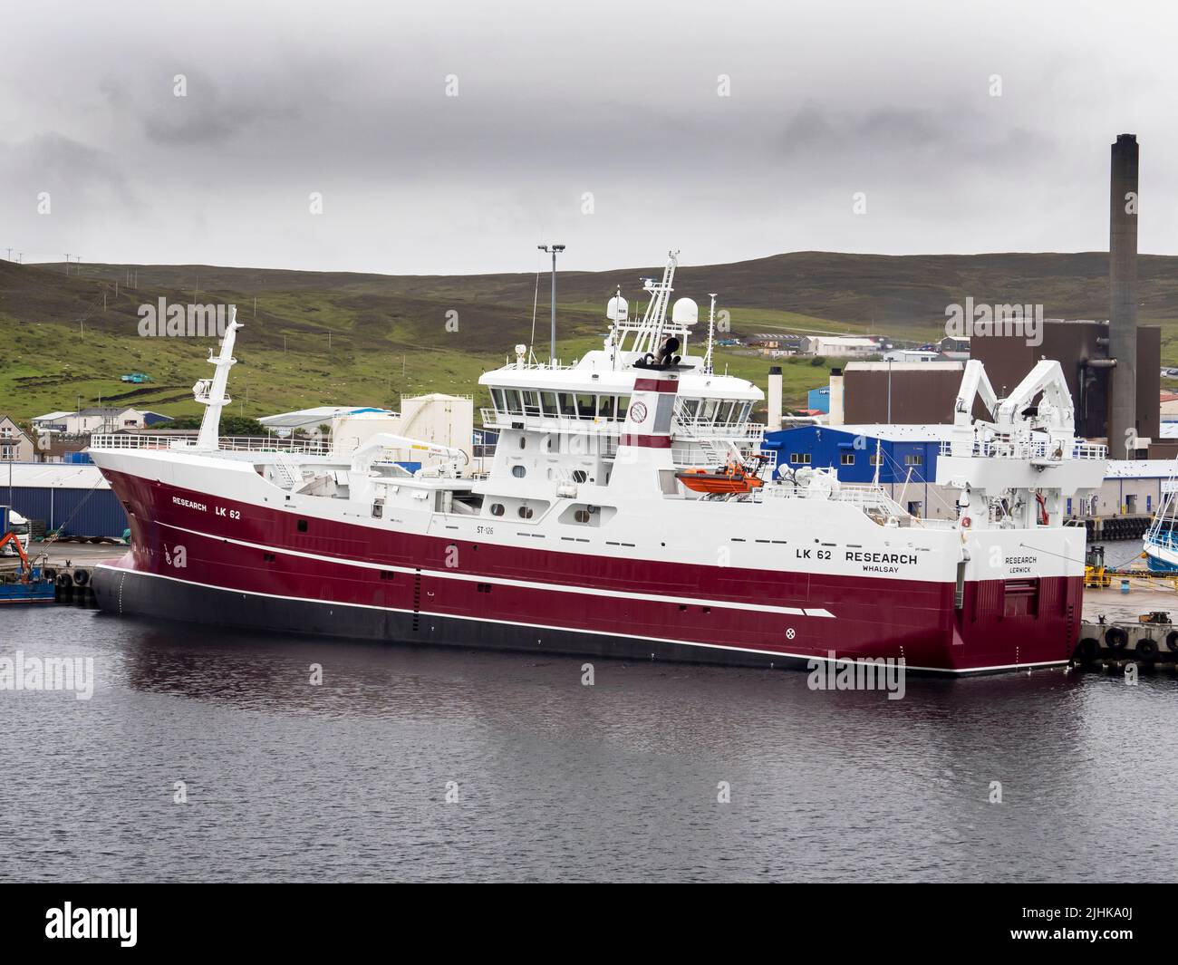Un buque de investigación con la central combinada de calor y electricidad detrás, en Lerwick, Mainland Shetland, Escocia, Reino Unido. Foto de stock