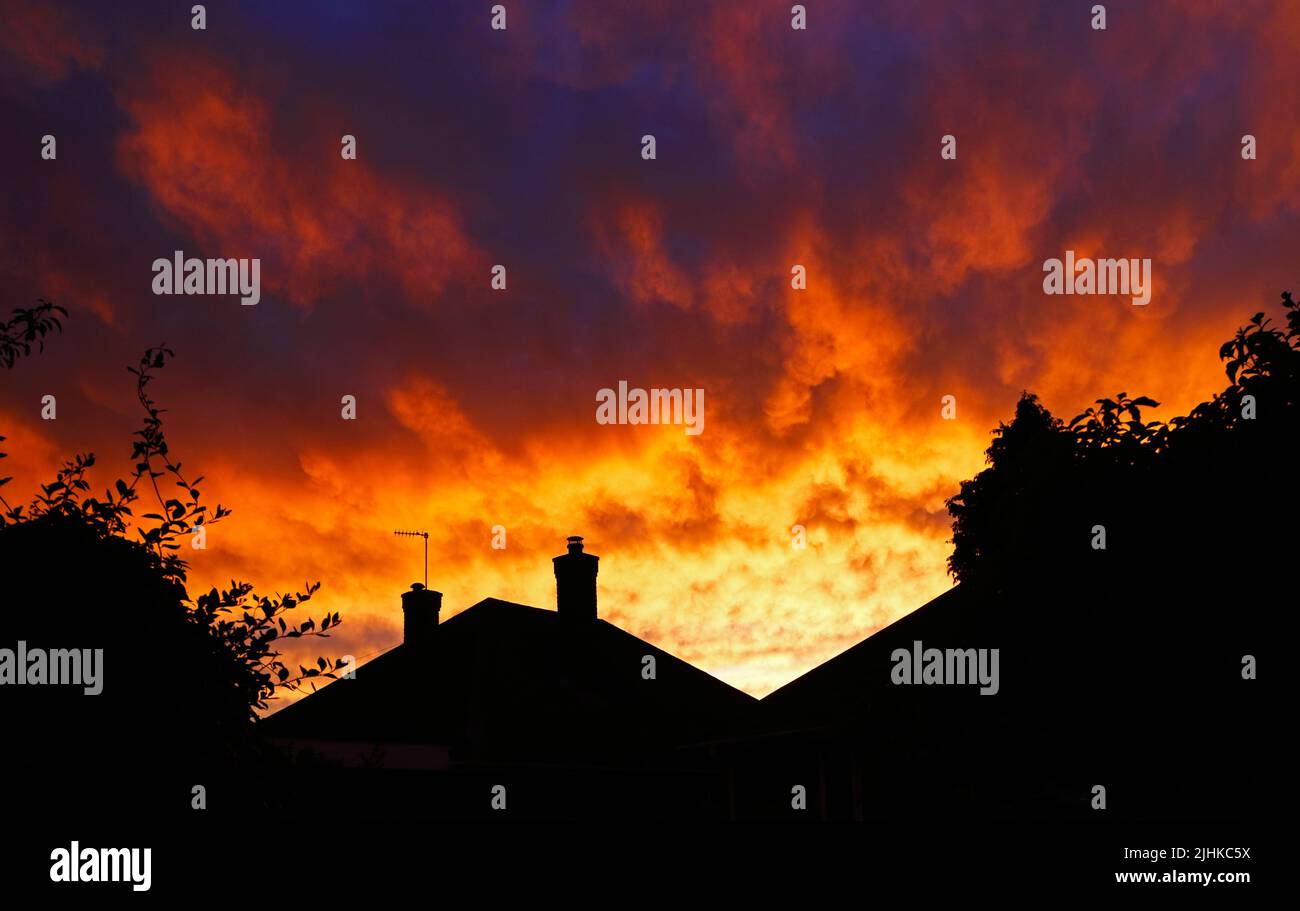Un fenómeno de un cielo brillantemente coloreado al atardecer causado por el exceso de partículas de polvo que migran desde el norte de África en Hellesdon, Norfolk, Inglaterra, Reino Unido. Foto de stock