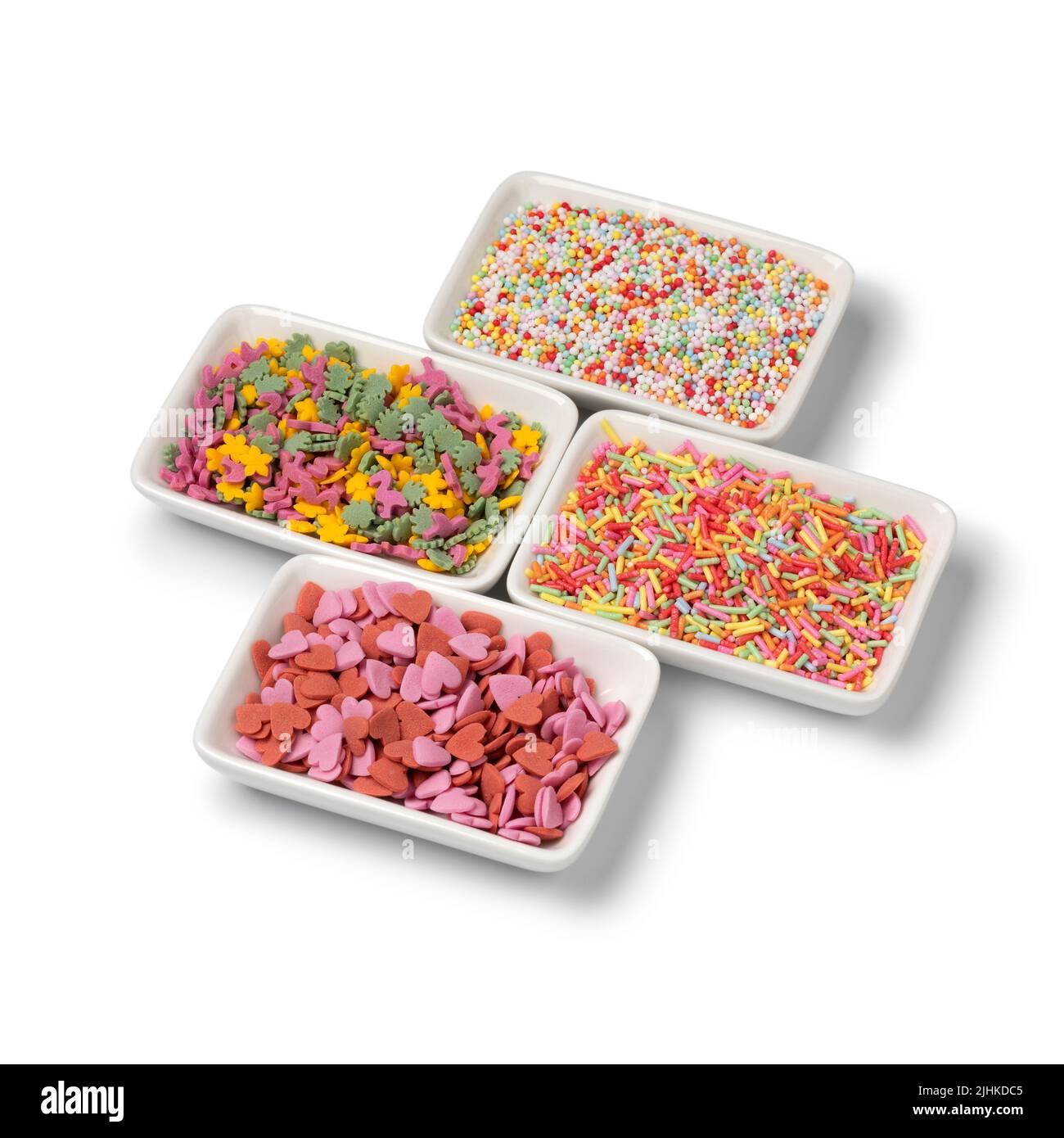Pequeños cuencos con coloridos espolones de azúcar para decorar la pastelería casera aislada sobre fondo blanco Foto de stock