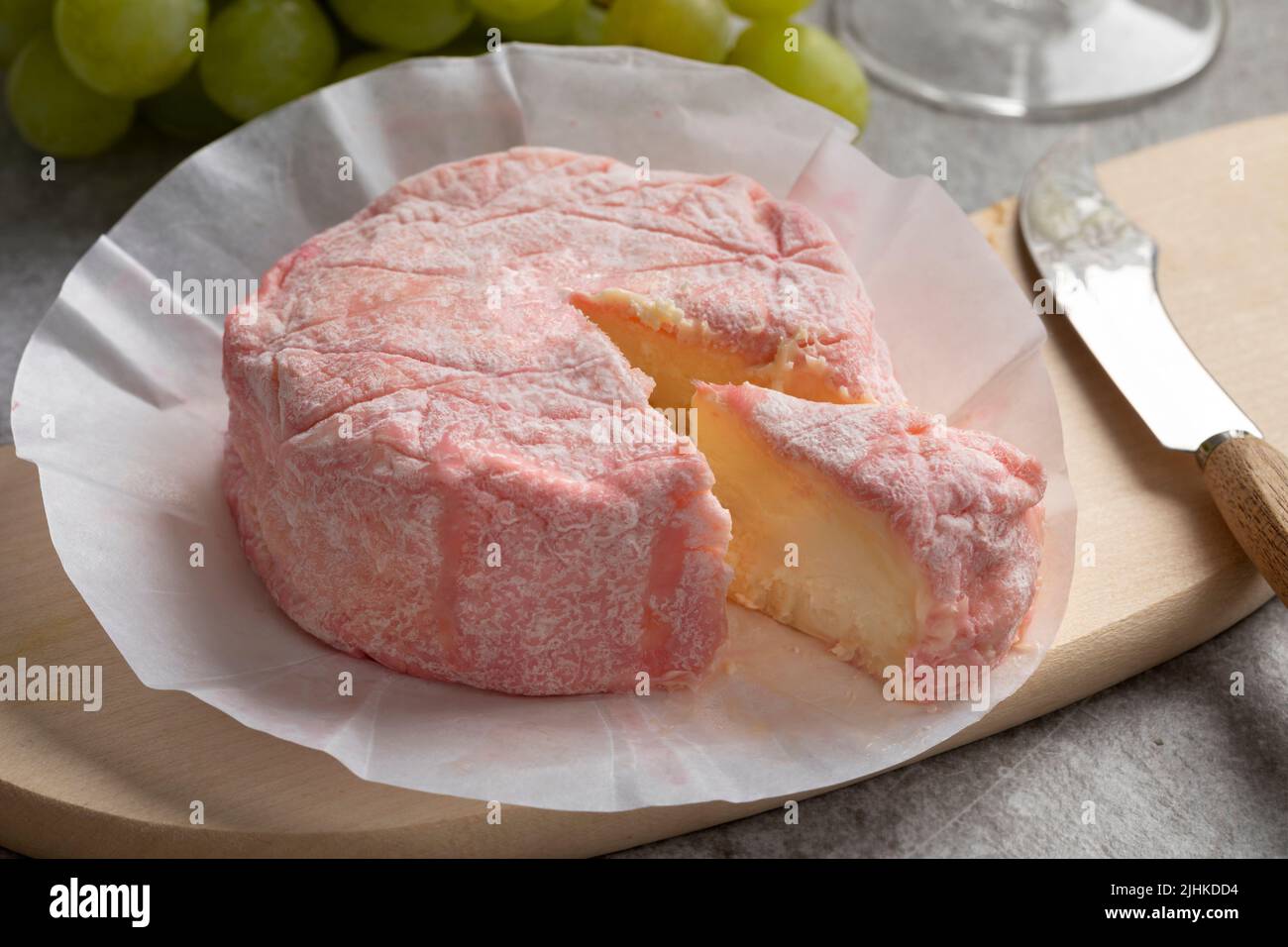 Le rose, queso francés suave con leche de vaca y refinado con champán rosado y un trozo de primer plano sobre una tabla de cortar Foto de stock