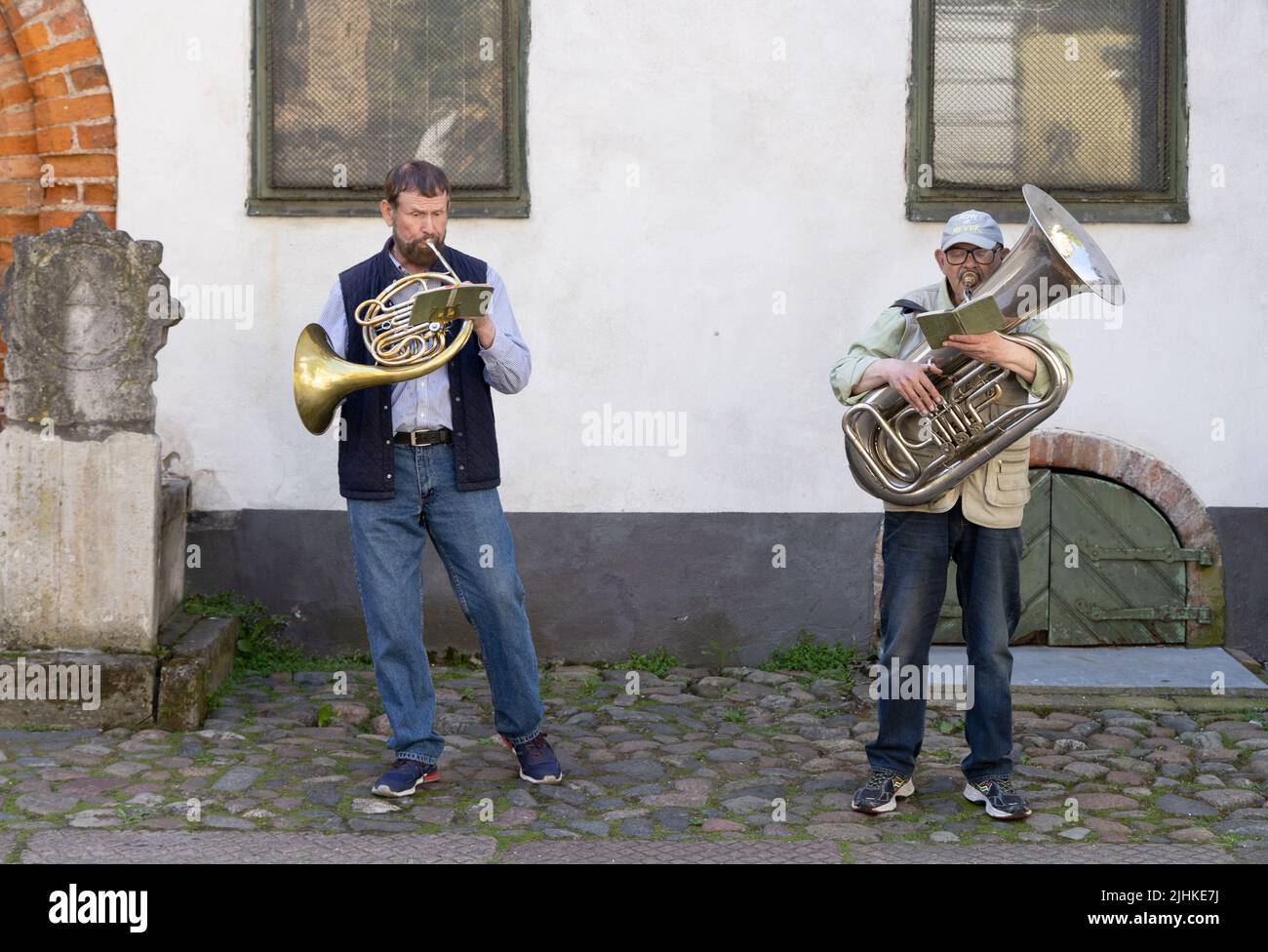Músicos callejeros - Dos hombres de mediana edad de 50s años tocando el cuerno francés y la tuba en las calles del casco antiguo de Riga, Riga Letonia Europa; - Riga Lifestyle Foto de stock