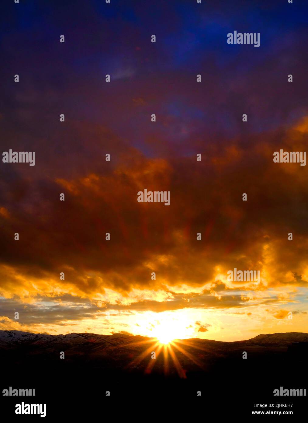 Puesta de sol sobre las montañas horizonte nubes sunstar sun star brillante brillante Foto de stock