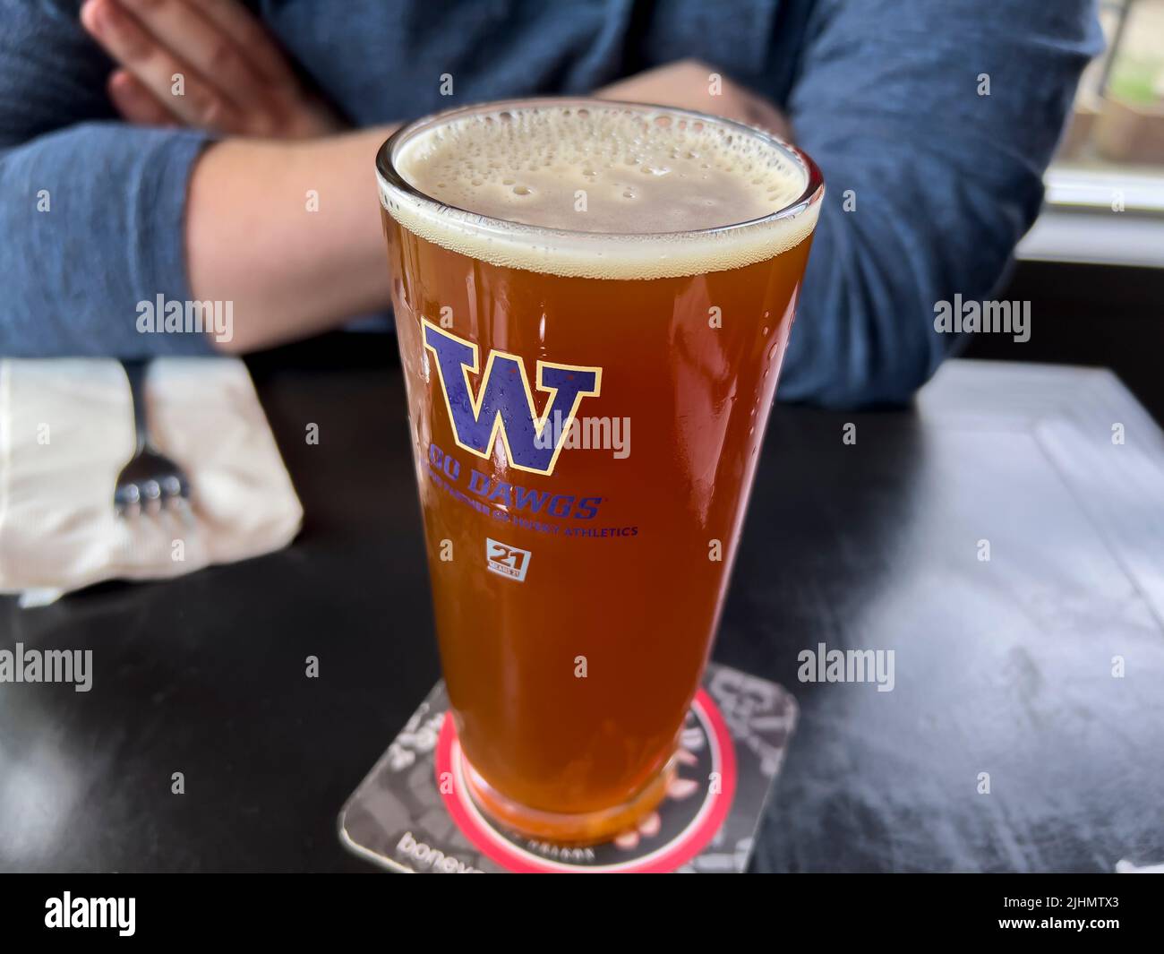 Seattle, WA EE.UU. - Hacia el 2022 de junio: Vista de cerca de una cerveza espumosa en un vaso de la Universidad de Washington dentro de un bar local. Foto de stock