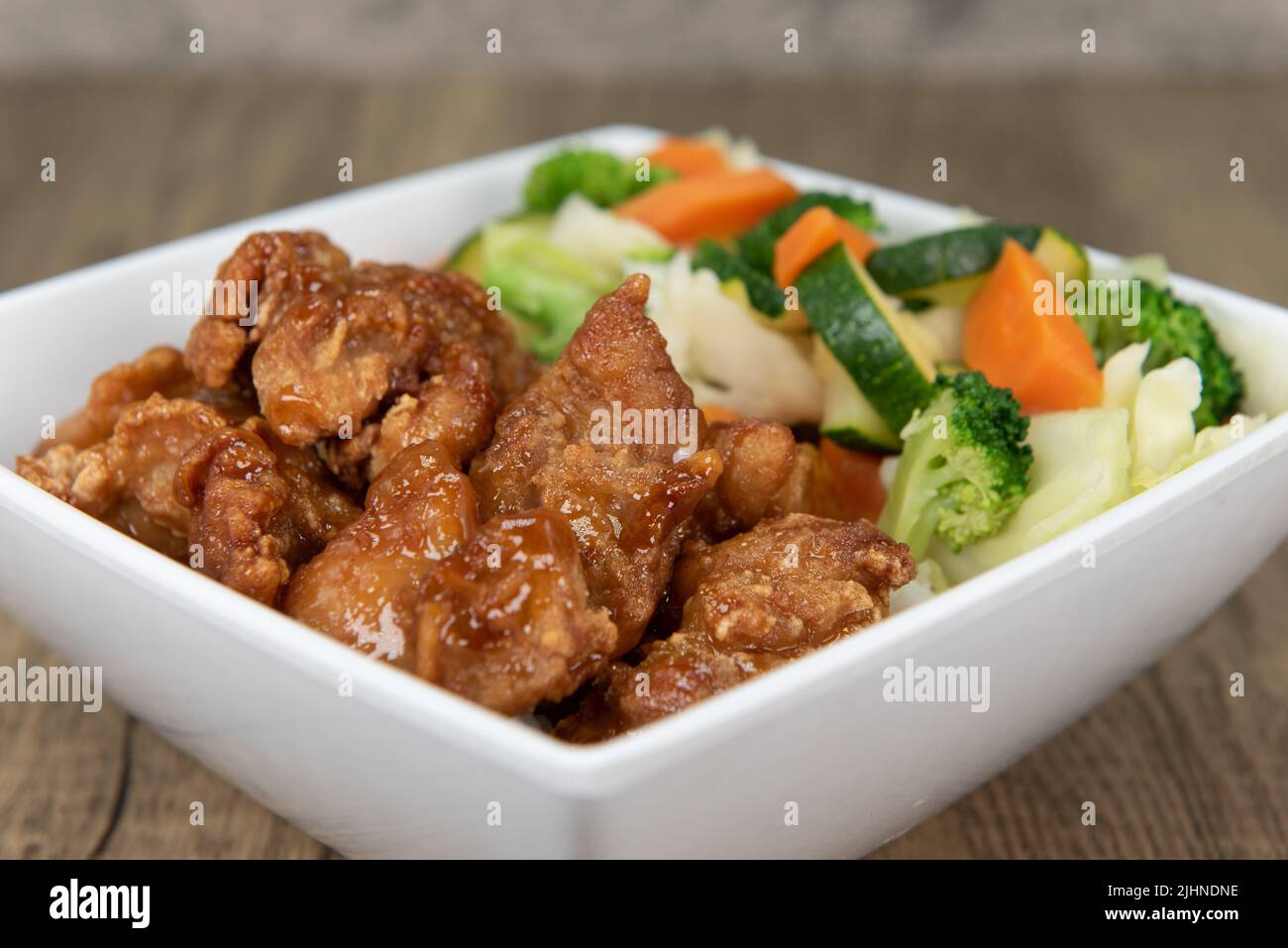 La comida de la cocina china tentadora que consiste en pollo anaranjado sobre arroz con verduras asegurará que el vientre estará lleno. Foto de stock