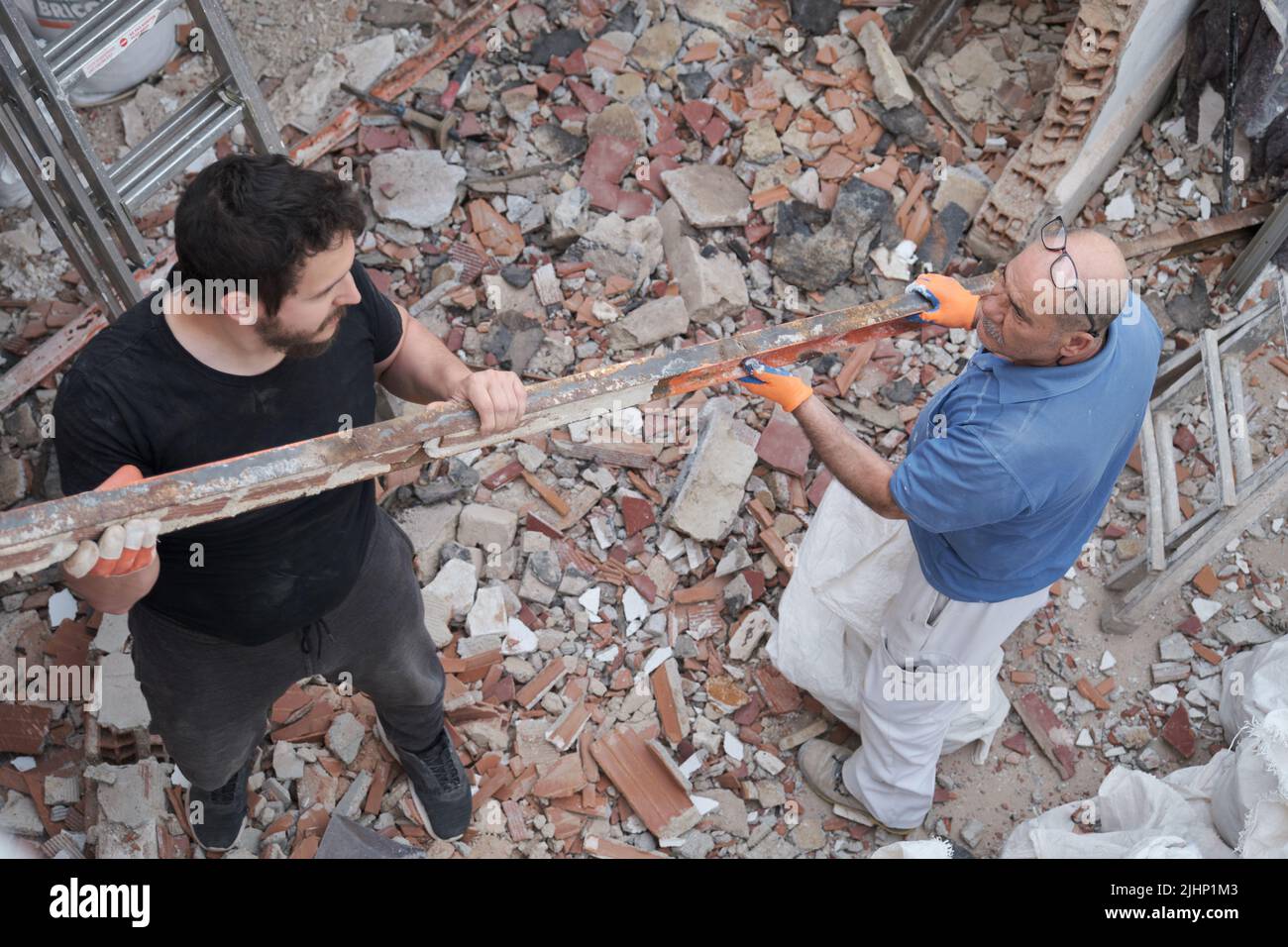 Dos trabajadores retirando viejas vigas metálicas en una casa de construcción. Foto de stock