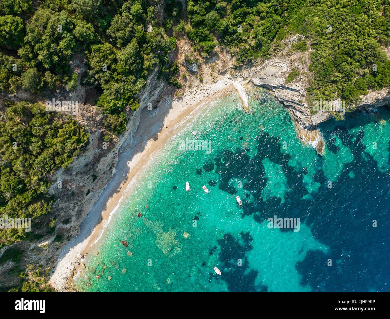 Vista aérea de la playa de Kolias en la isla de Corfú. Grecia. Acantilados con vistas a la playa y un mar verde y azul no contaminado. Barcos amarrados Foto de stock