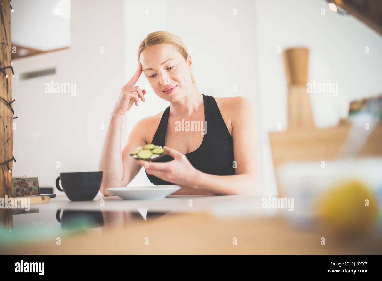 Hermosa mujer embarazada deportiva teniendo un aperitivo saludable en la cocina de casa. Concepto de estilo de vida saludable. Foto de stock