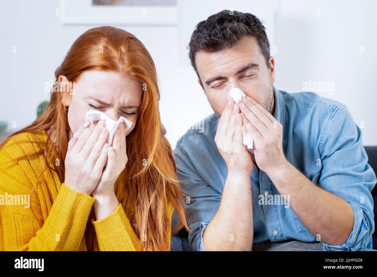 Una pareja enferma se sopla la nariz sufriendo los síntomas de la gripe juntos Foto de stock