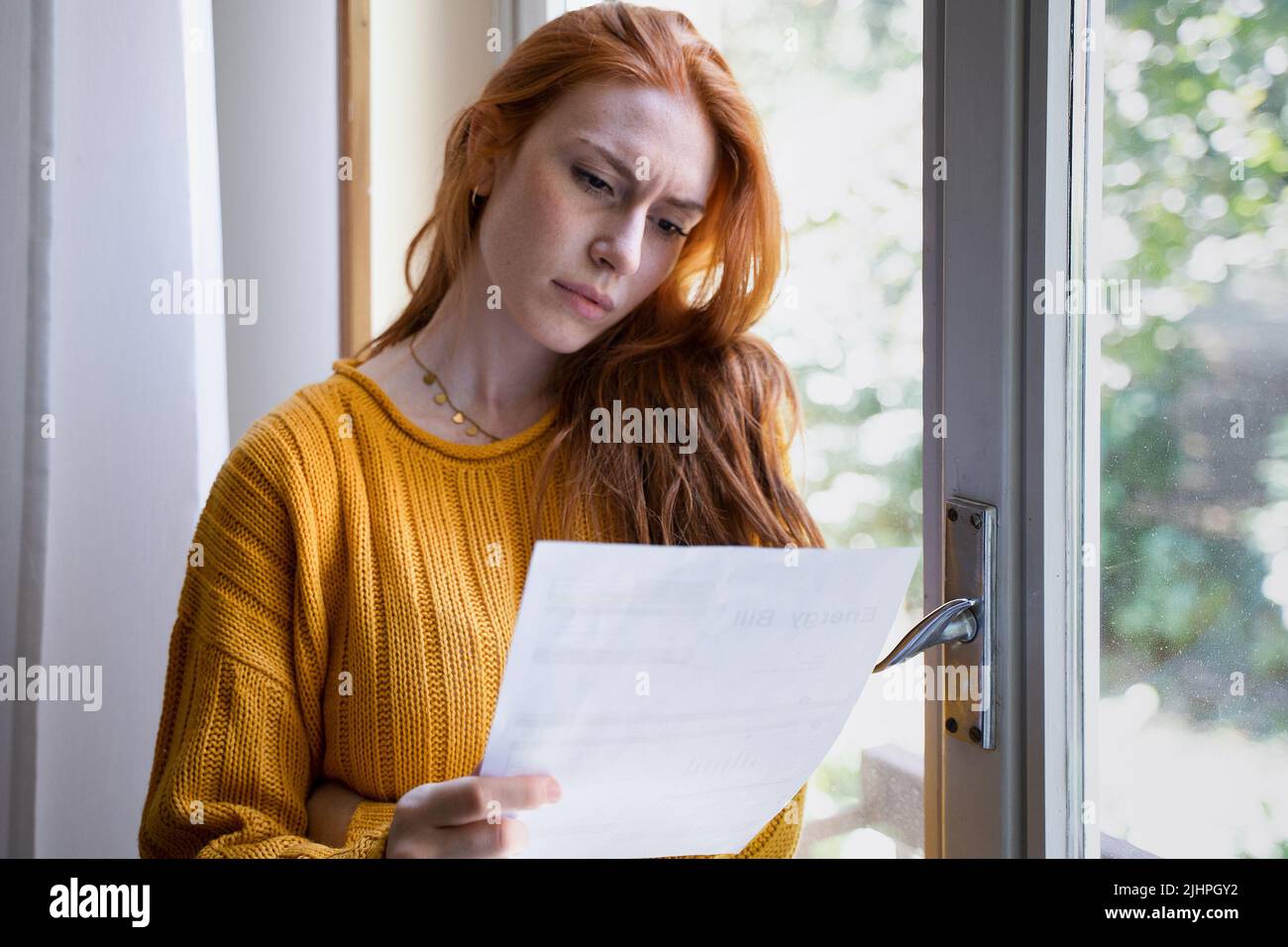 Mujer preocupada leyendo notificación de malas noticias en casa Foto de stock