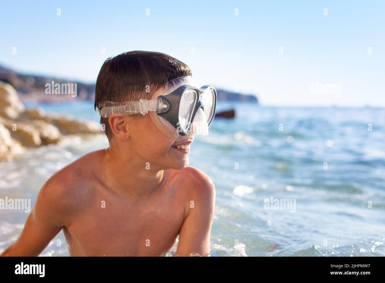 Feliz muchacho caucásico con gafas en el mar mirando lejos Foto de stock