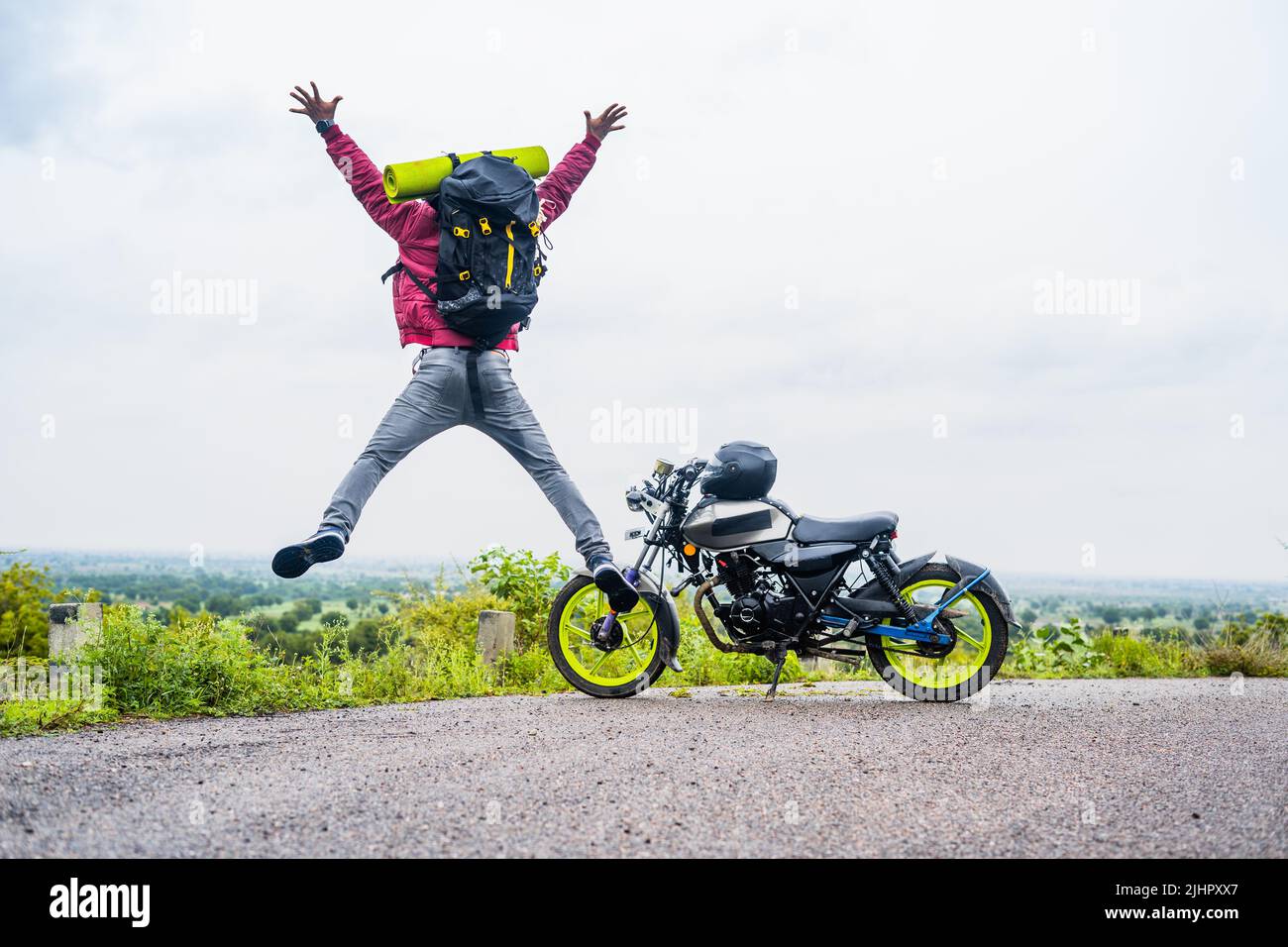 Moto viajero celebrar la naturaleza o después de llegar a destino en la cima de la colina por gritos y saltos - concepto de aventuras, juguetón y Foto de stock