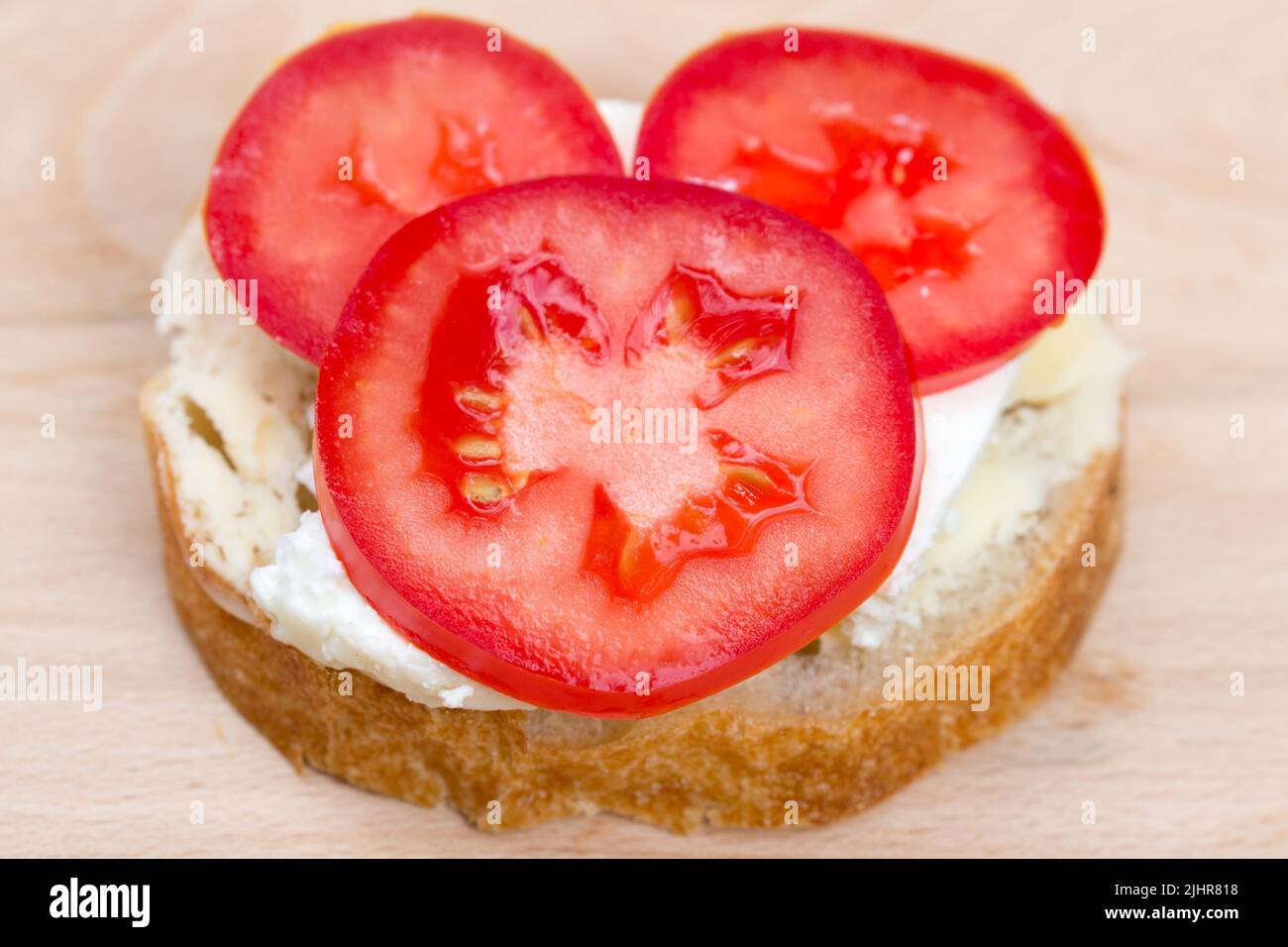 pequeño sándwich abierto con requesón y tomate sobre tabla de madera Foto de stock