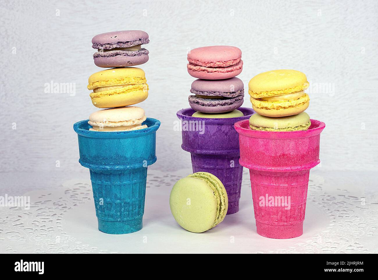 Macarrones franceses apilados en coloridas tazas de helado Foto de stock