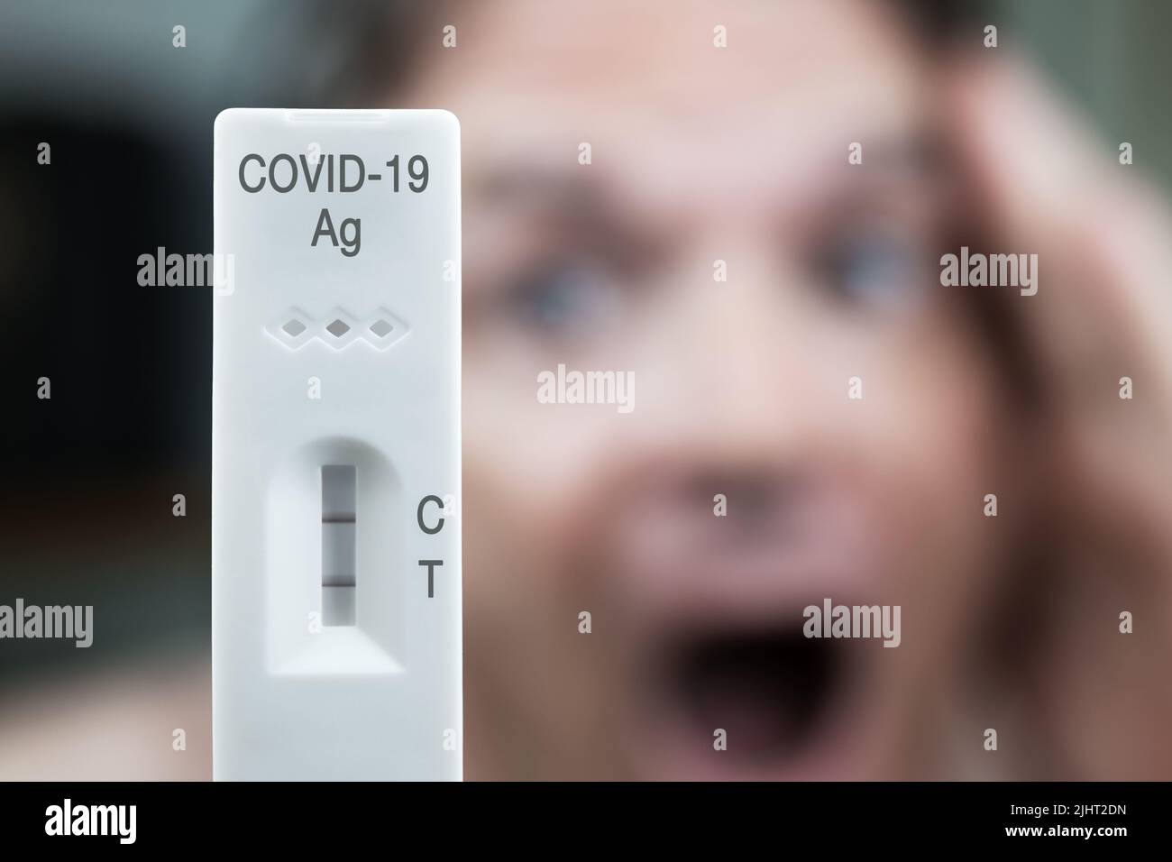 COVID-19 prueba rápida positiva con cara masculina borrosa, gritando. Foto de stock