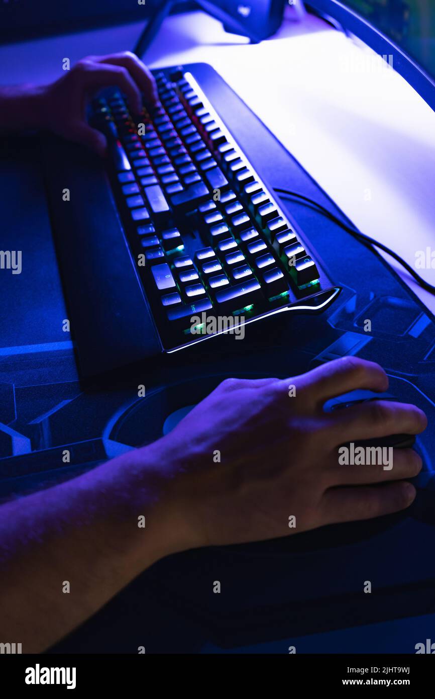 Toma vertical de manos con un ratón y un teclado jugando en un PC en una  habitación con luz azul Fotografía de stock - Alamy