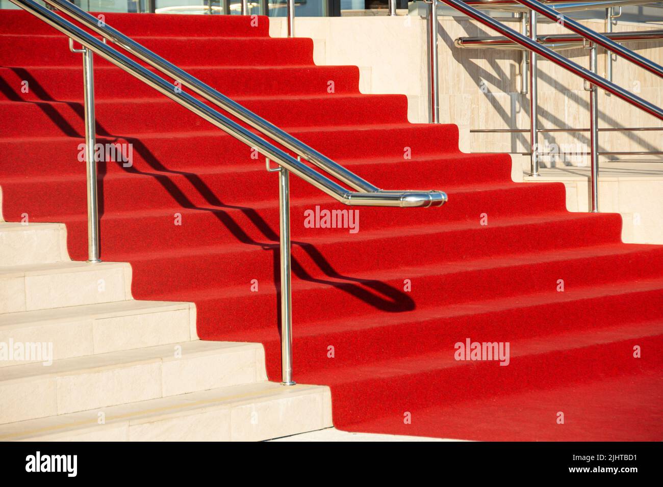 Alfombra roja en las escaleras en un interior de lujo fuera al aire libre y pasamanos de metal brillante cromado Foto de stock