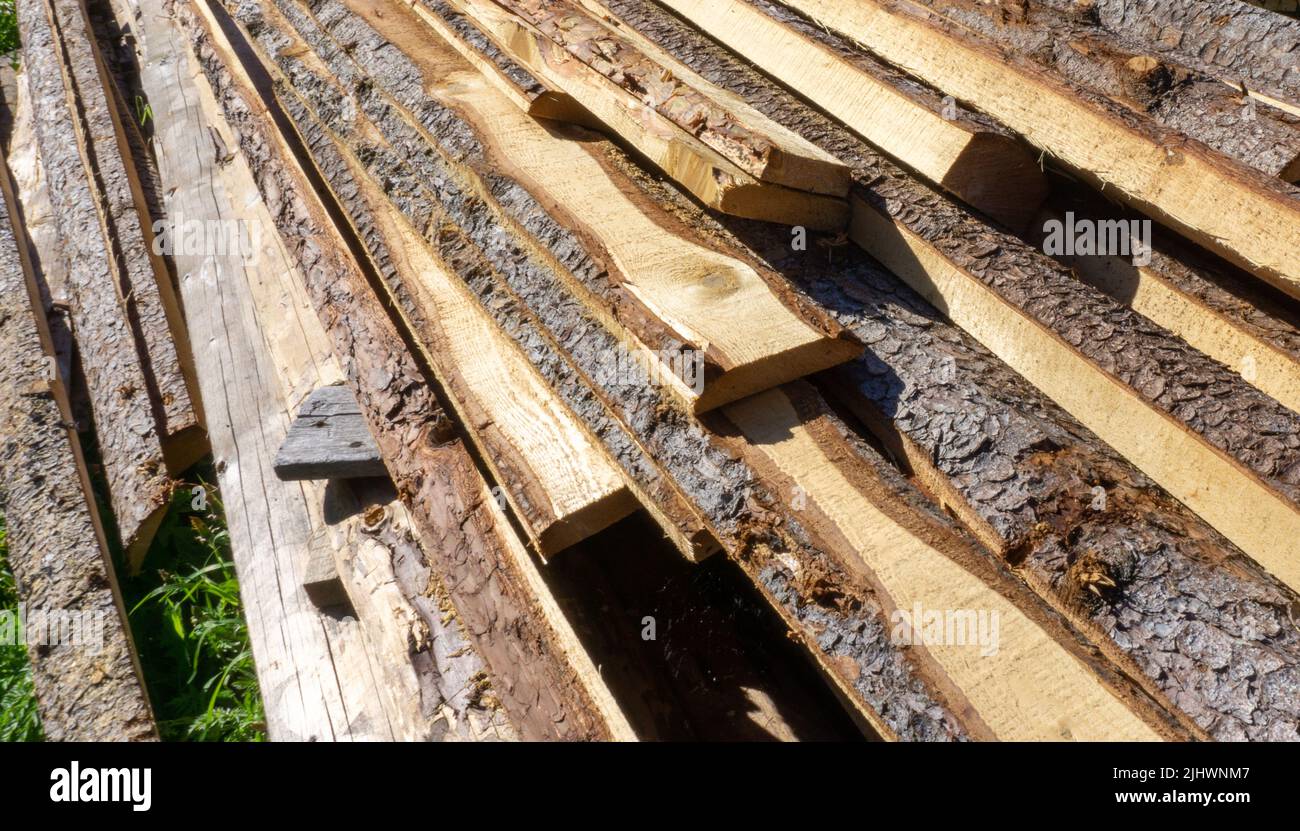 Tablas de madera con corteza de croaker yace en el suelo. Leña de aldea, material de