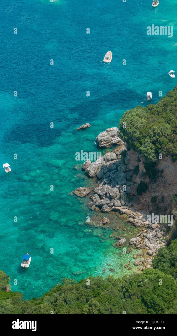 Vista aérea de la playa de Klimatia, cerca de la playa de Limni en la isla de Corfú. Línea costera. Aguas transparentes y cristalinas, barcos amarrados y bañistas. Foto de stock