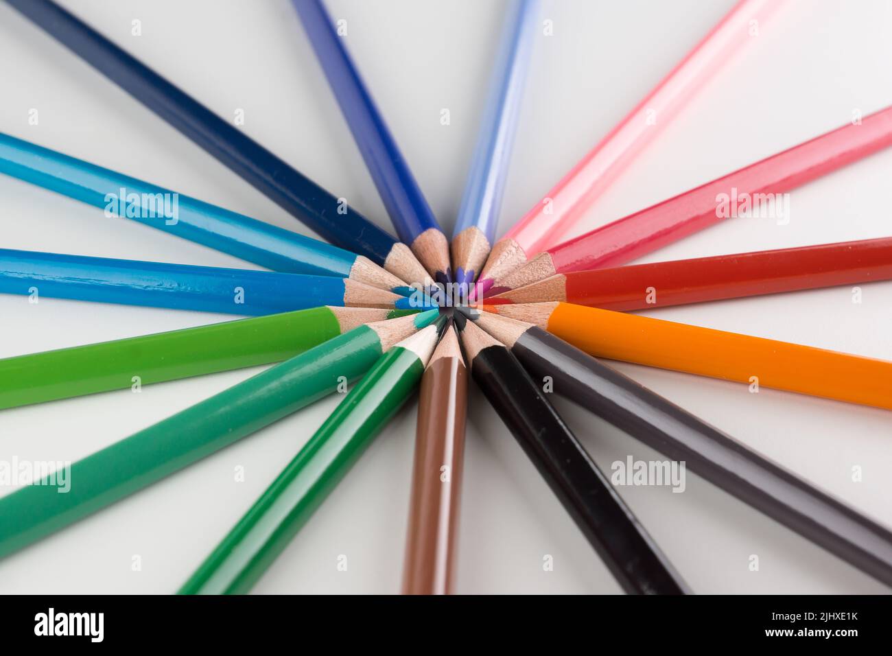 juego de lápices de colores alineados con un arco sobre fondo blanco Foto de stock