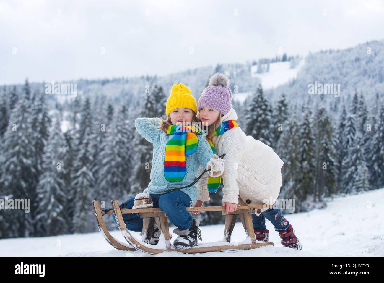 Niña del niño caucásico en ropa de invierno caliente y orejeras esponjosas  rosadas, sonríe a la cámara, construyendo muñeco de nieve al aire libre  Fotografía de stock - Alamy