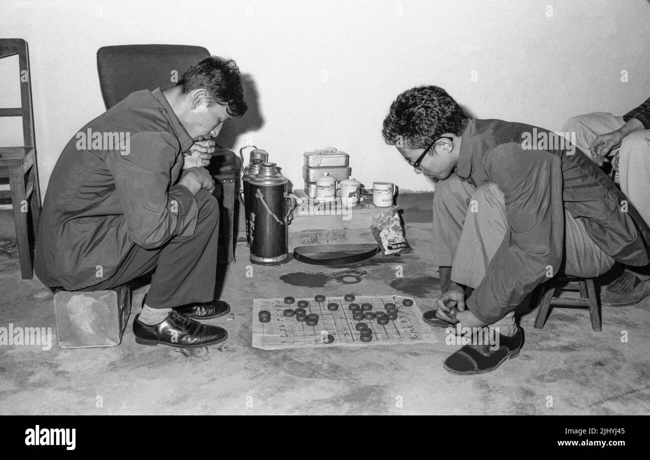 CHINA XIAN twoo los hombres están en cuclillas con un juego de mesa entre ellos Foto de stock