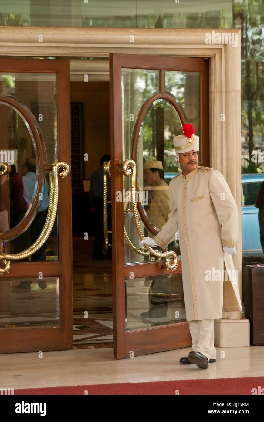 El hombre de la puerta abre la puerta de entrada en el hotel, Mumbai, la India Foto de stock