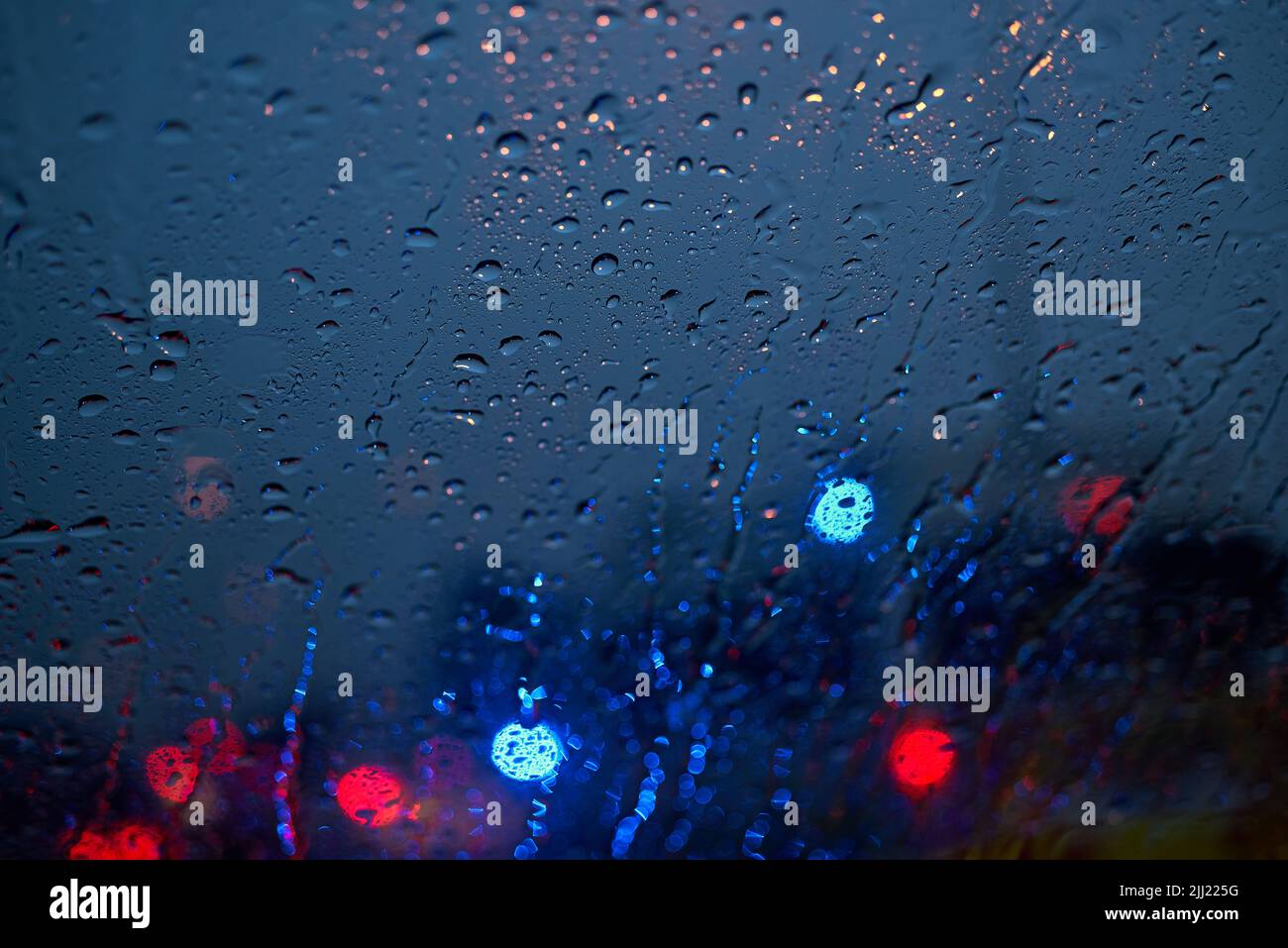 Luz del tráfico y coche en una noche lluviosa a través del parabrisas Foto de stock