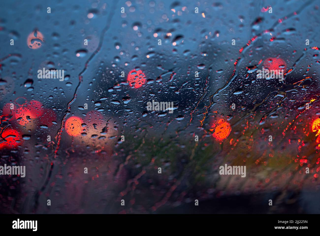 Luz del tráfico y coche en una noche lluviosa a través del parabrisas Foto de stock