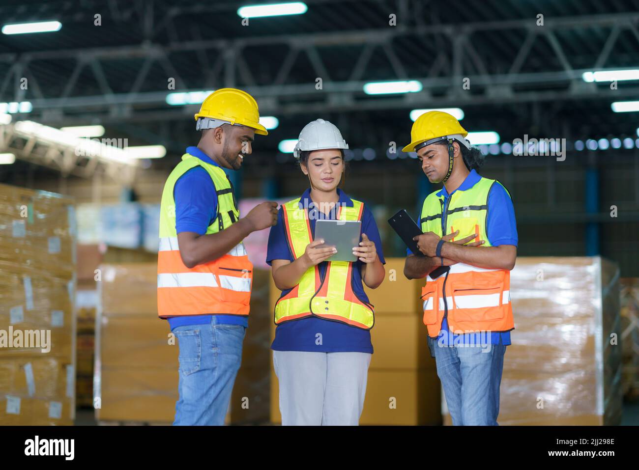 Los trabajadores de almacén del equipo asiático que comprueban el estado del envío en el tablet PC digital se preparan para la entrega al cliente. Trabajo en equipo de los empleados. Foto de stock