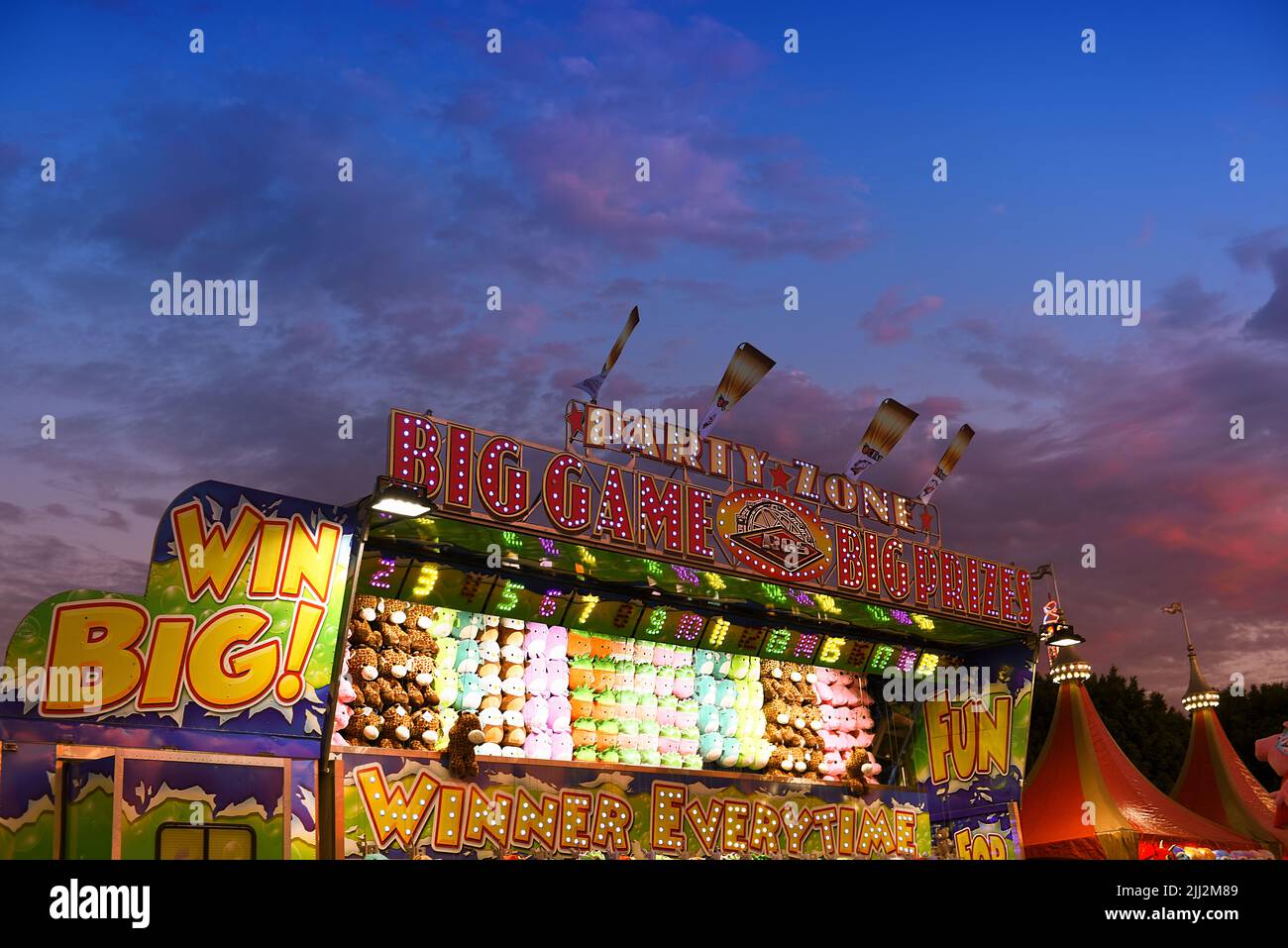 COSTA MESA, CALIFORNIA - 20 JUL 2022: Partido de carnaval de Party Zone en la Feria del Condado de Orange con cielo de puesta de sol a la hora azul. Foto de stock