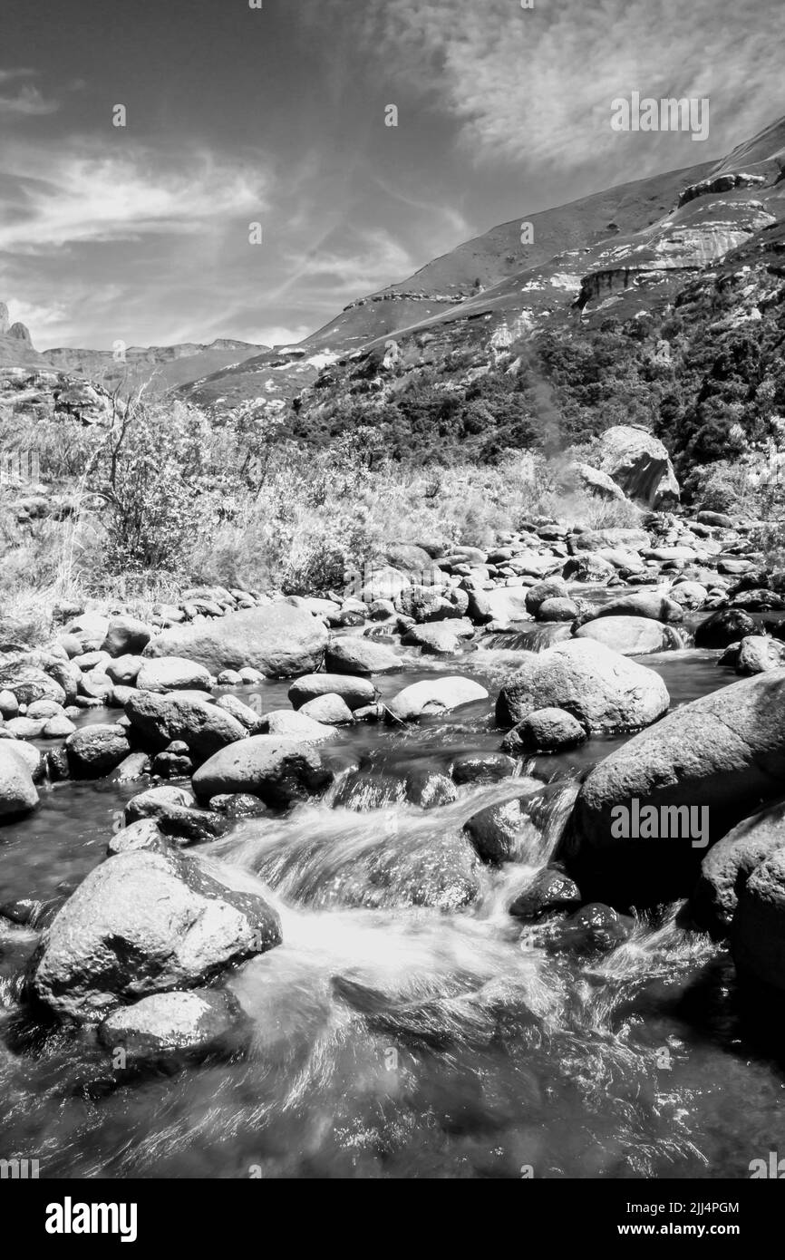 Vista en blanco y negro de un río de montaña que fluye rápidamente en las montañas Drakensberg de Sudáfrica Foto de stock